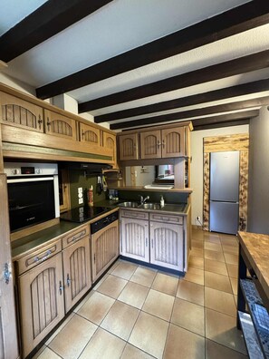 Eine Küche mit Holzausstattung, einem Bosch-Backofen, einer Spüle und einem Kühlschrank.