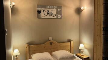 A bedroom with a wooden headboard, two bedside lamps, a bed with white bedding, and a wall-mounted artwork with the word "HOPE".