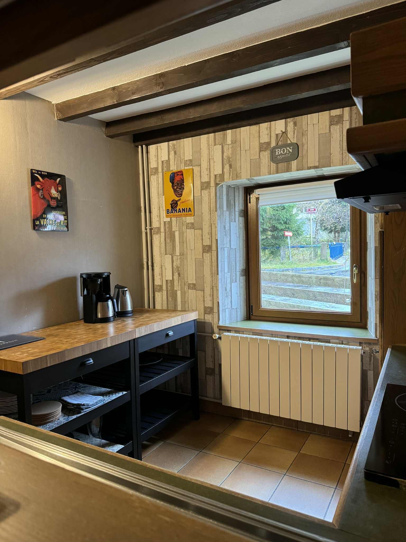 Une cuisine avec un plan de travail en bois, une machine à café et une fenêtre donnant sur l’extérieur.