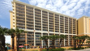 A multi-story hotel with a symmetrical facade, balconies, and a landscaped area with palm trees. - Family Fun at this Beachside Resort in Myrtle Beach (Myrtle Beach)