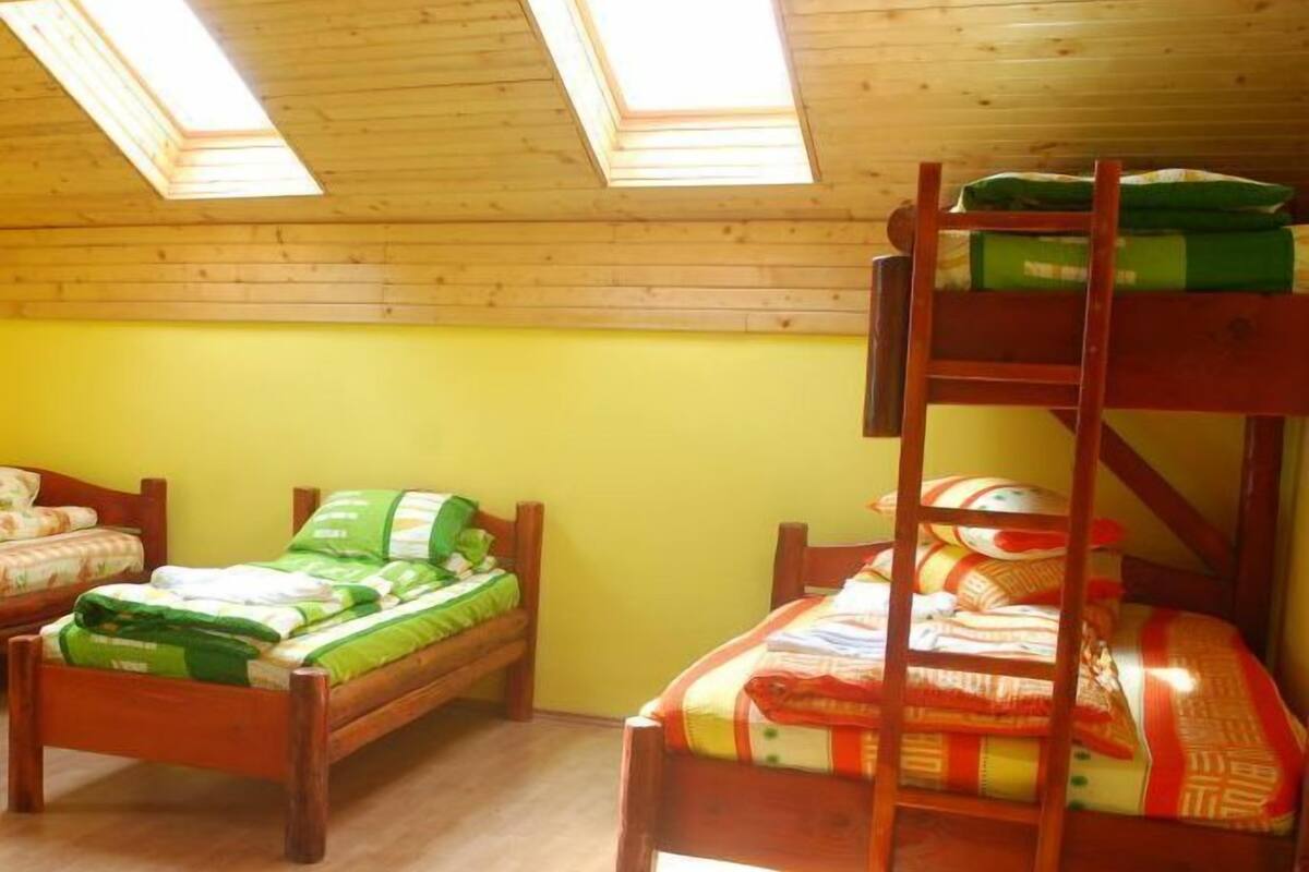 A dormitory room with two bunk beds, a skylight, and a wooden floor.
