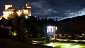 Un castillo con una torre, rodeado de árboles y un pequeño estanque.