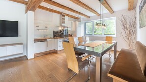 Una cocina moderna con vigas de madera, un comedor con mesa de vidrio y un sofá.