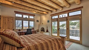 Ein Schlafzimmer mit einem großen Bett, Holzbalkendecke, Schreibtisch und Blick ins Freie.