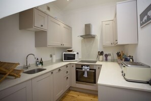 A compact kitchen with white cabinets, a microwave, a toaster, and a sink. - Quiet, City Garden Apt. Pets Allowed (PL) (Bath)