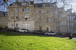 A row of parked cars along a street with a building in the background. - Quiet, City Garden Apt. Pets Allowed (PL) (Bath)