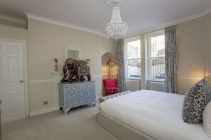A bedroom with a large bed, a dresser, a mirror, and a chandelier. - Quiet, City Garden Apt. Pets Allowed (PL) (Bath)