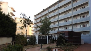 A multi-story residential building with balconies, a paved pathway, and some greenery. - Residencial complex les marines  (Roses)