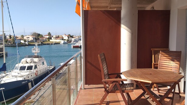 A balcony with a table and chairs, overlooking a marina with boats. - Residencial complex les marines  (Roses)