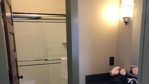 Een badkamer met een douchecabine van glas, een wit toilet, een bad en een wastafel met spiegel.