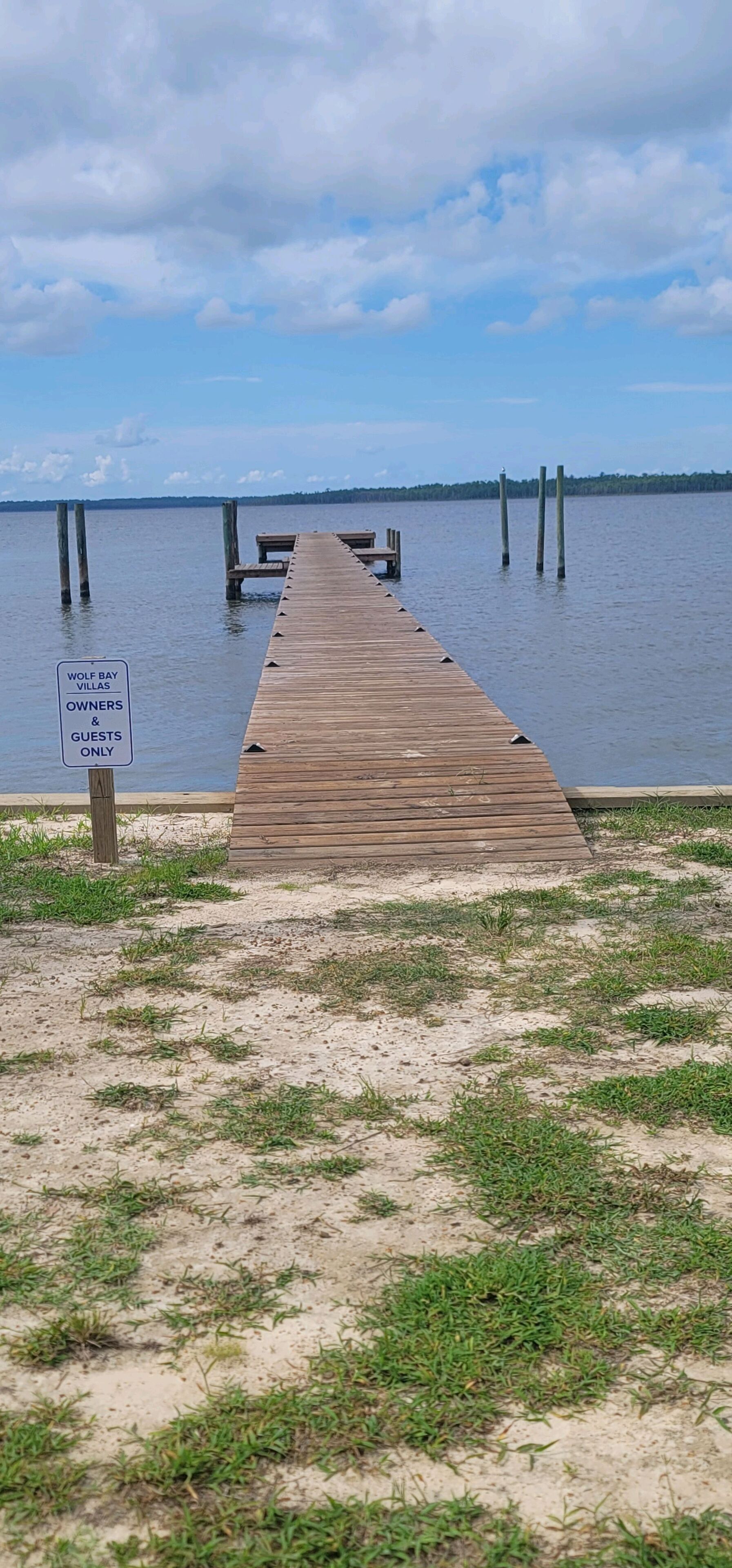 A wooden pier leading to a body of water with a sign indicating it is for owners and guests only.