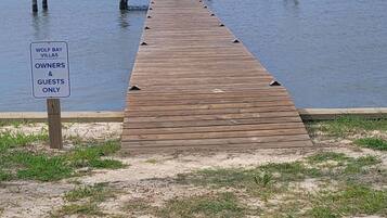 A wooden pier leading to a body of water with a sign indicating it is for owners and guests only.