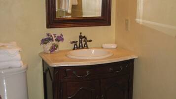 A bathroom with a wooden vanity, a white sink, and a mirror above the sink.