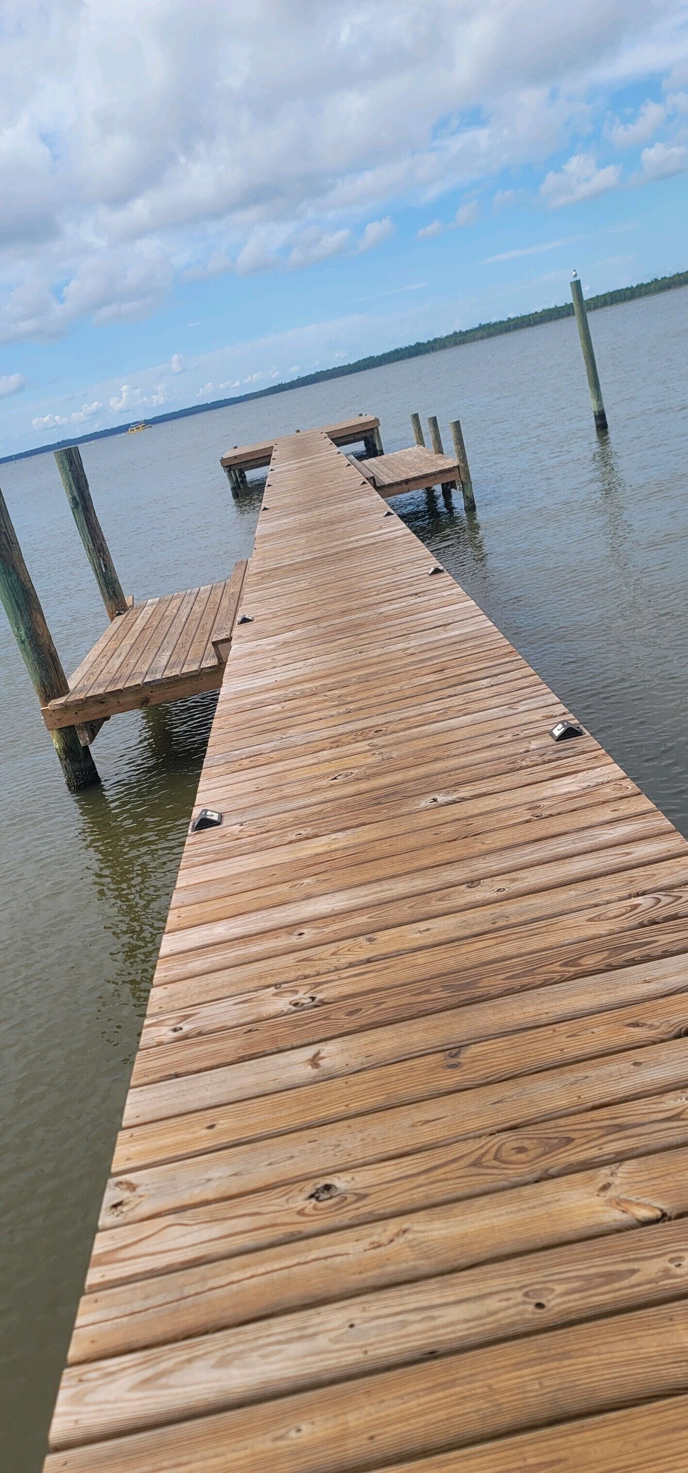 A wooden pier extending into calm water with a clear sky above.