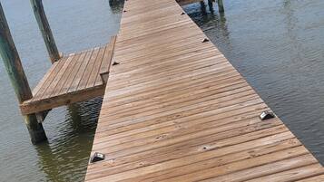 A wooden pier extending into calm water with a clear sky above.