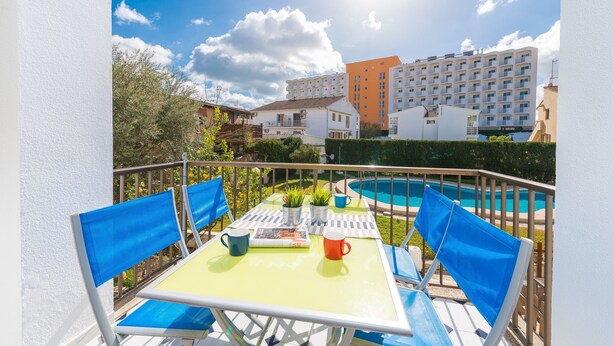 A balcony with a table, chairs, and a pool.