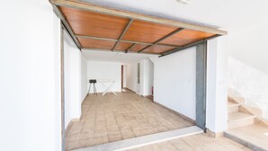 A spacious hallway with a tiled floor, a wooden ceiling, and a staircase on the right.