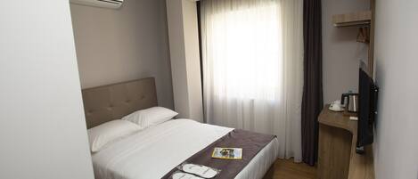 Ein Hotelzimmer mit Bett, Schreibtisch, Fernseher und Klimaanlage.