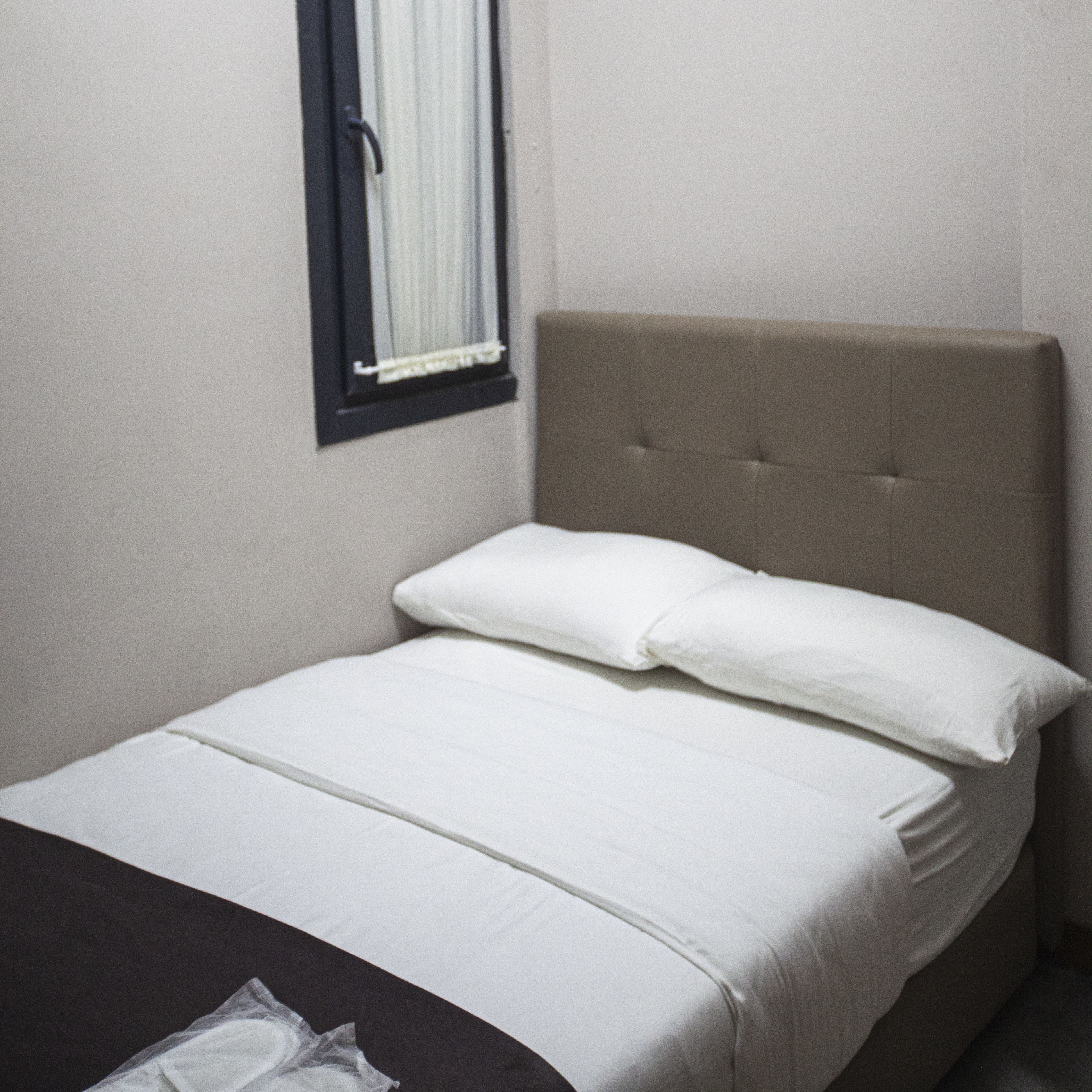 A single bed with white bedding and a headboard in a hotel room.