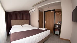 A hotel room with a large bed, an air conditioning unit, a wardrobe, a minibar, and a television. - Jurnal Hotel (Istanbul)