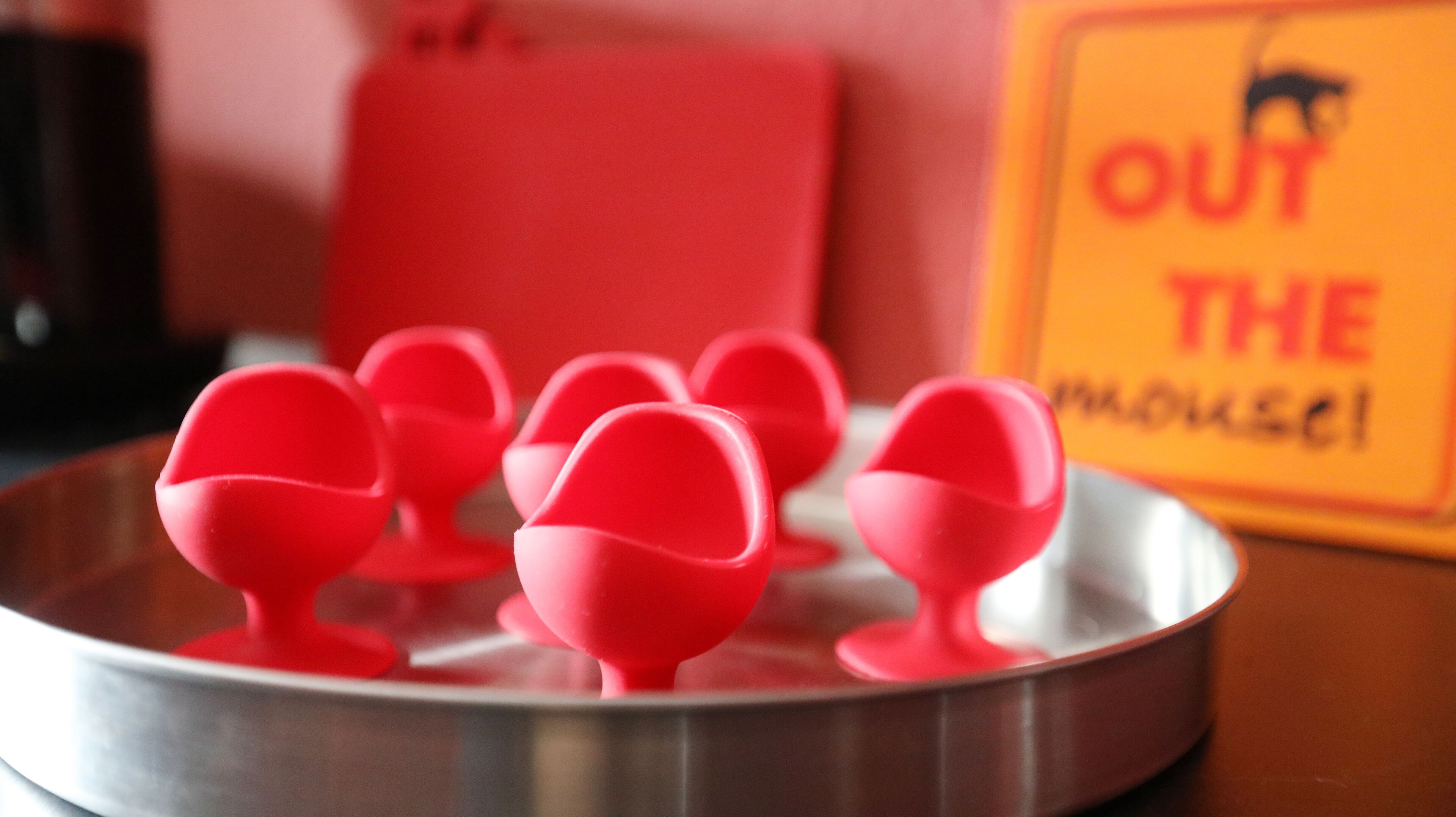 Un plateau contenant des objets rouges, une chaise rouge et un panneau avec du texte.