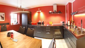 Una cocina moderna con gabinetes negros, una mesa de comedor de madera y una pared de acento roja.
