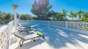 Uma área externa iluminada pelo sol, com espreguiçadeiras e um pérgola.