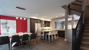 Cozinha moderna com ilha central, eletrodomésticos de aço inoxidável e área de jantar com parede em vermelho.