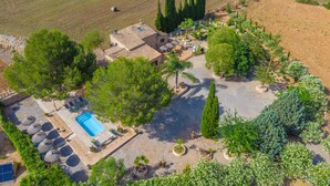 Vista aérea de una propiedad con piscina, mobiliario exterior y jardín ajardinado.