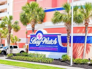 A sign for Bay Watch Resort & Conference Center with palm trees and a white truck in the foreground. - Baywatch 1607 (North Myrtle Beach)