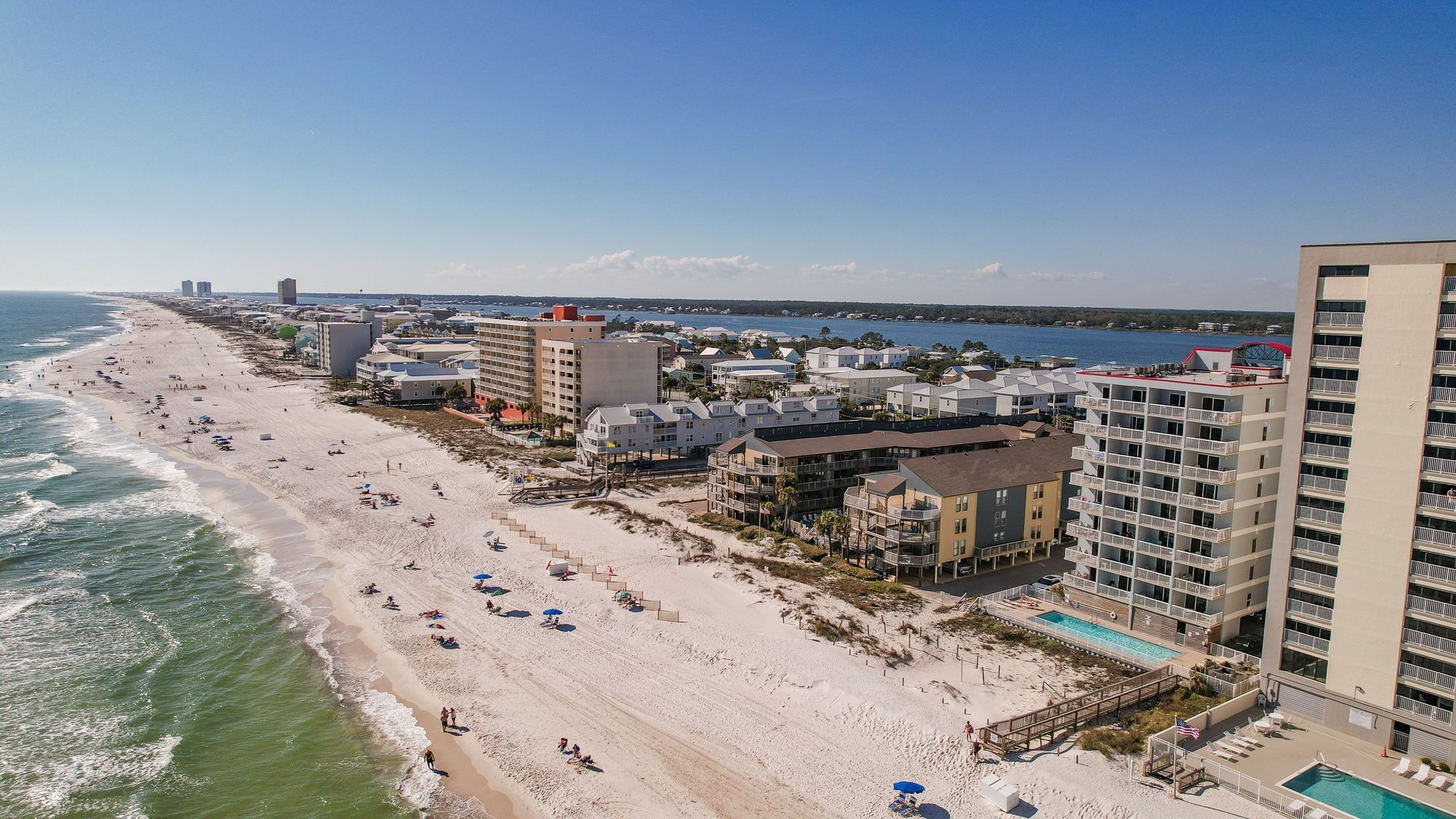 Un hôtel situé sur la côte, avec vue sur la plage, de nombreux balcons et une piscine.