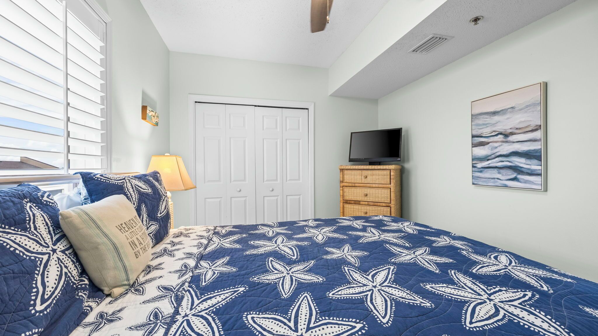 Un dormitorio con cama, televisión, cómoda y un cuadro en la pared.
