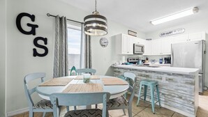 Una cocina moderna con armarios blancos, microondas integrado y refrigerador de acero inoxidable.