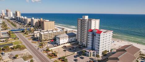 Un hotel costero con varios pisos, estacionamiento y vista a la playa y al océano.