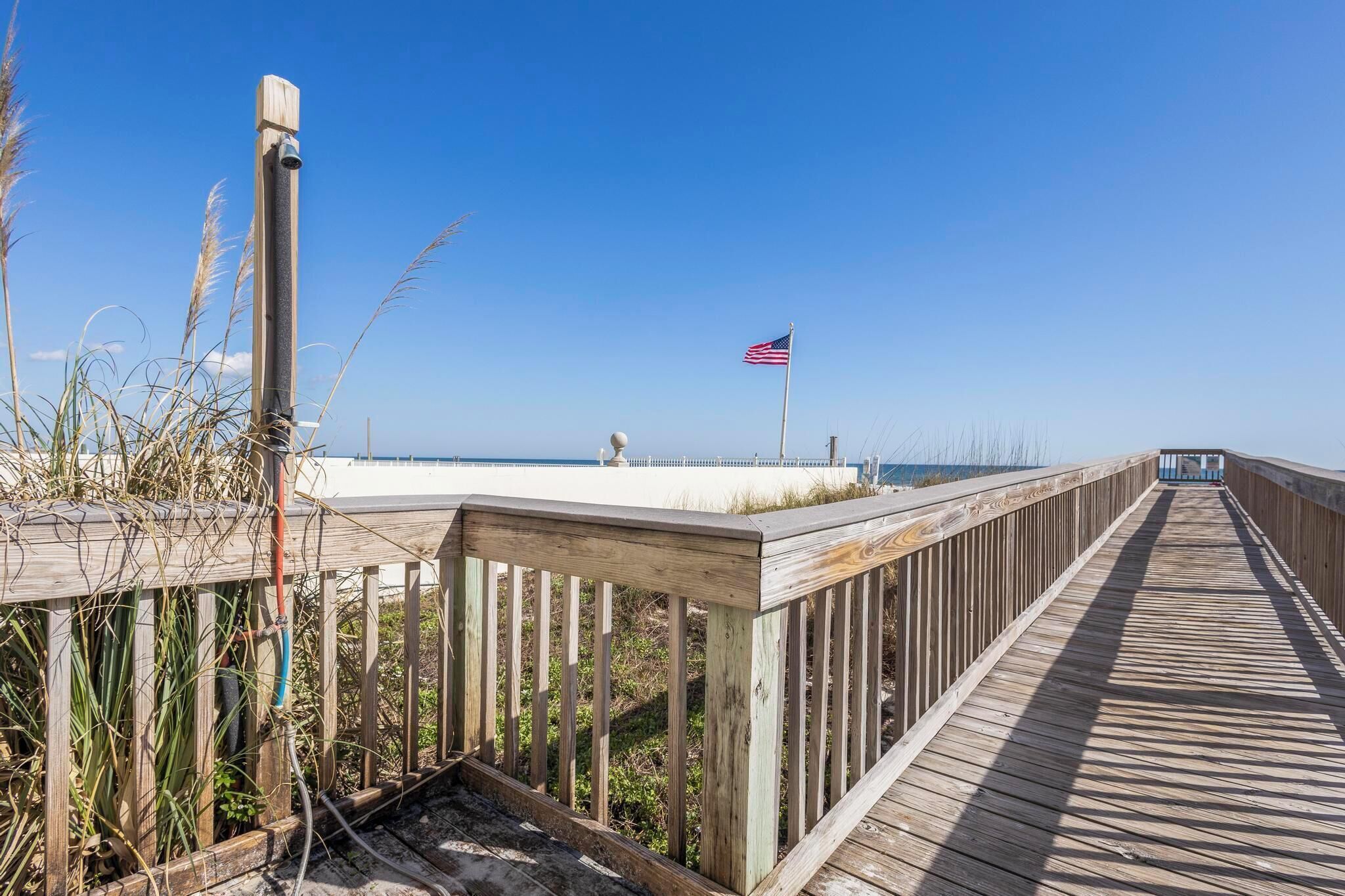 A wooden boardwalk leading to a beach with an American flag.