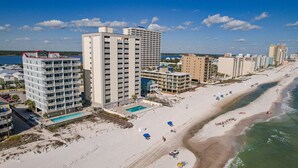 Un hotel costero con varios edificios altos, una playa y una piscina.