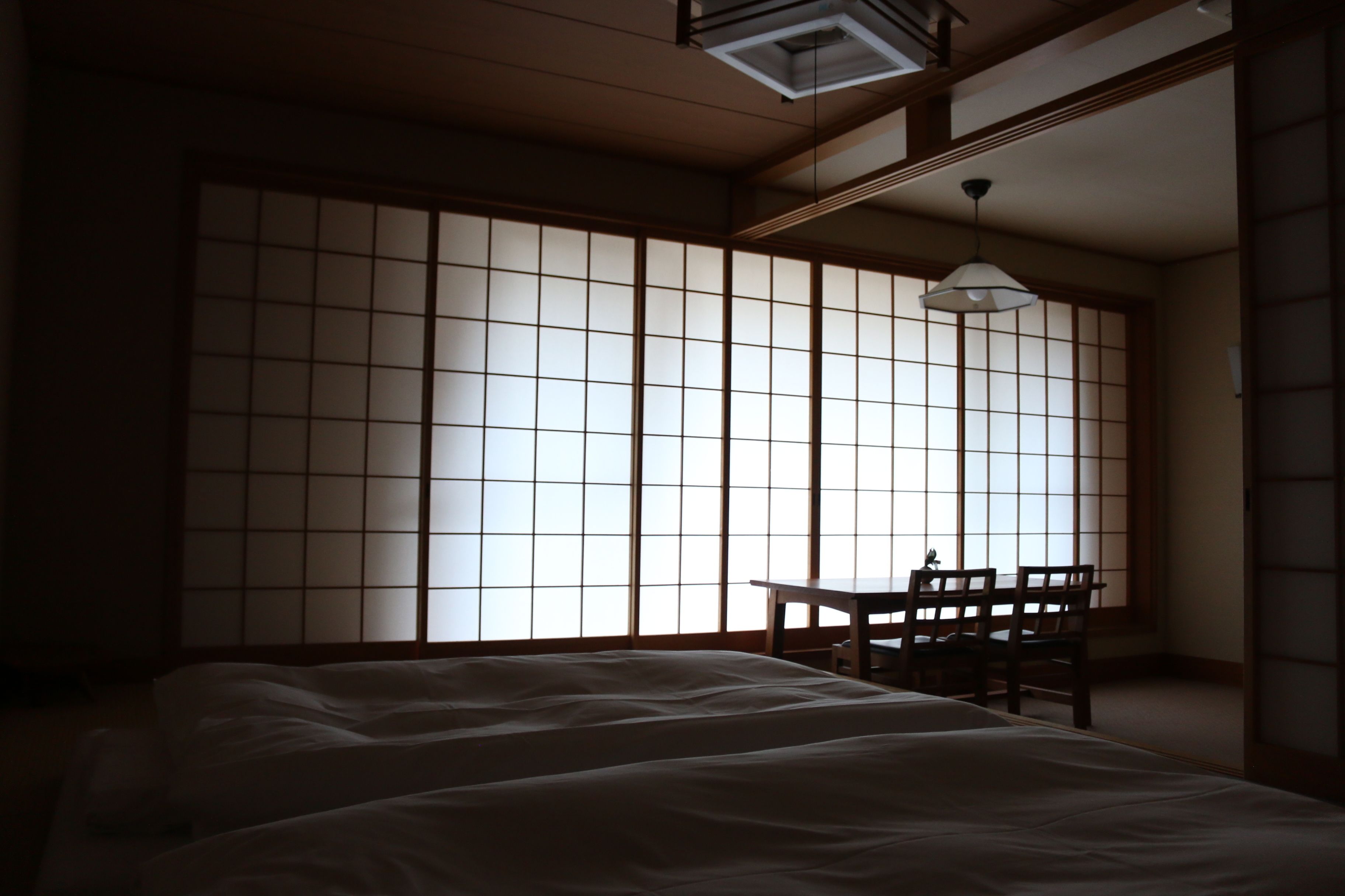 A traditional Japanese room with tatami flooring, a low wooden table, and a shoji screen door.