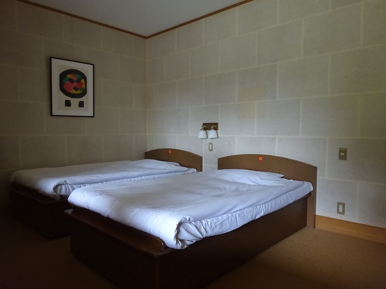 Quarto de hotel com duas camas, um quadro na parede e um abajur.