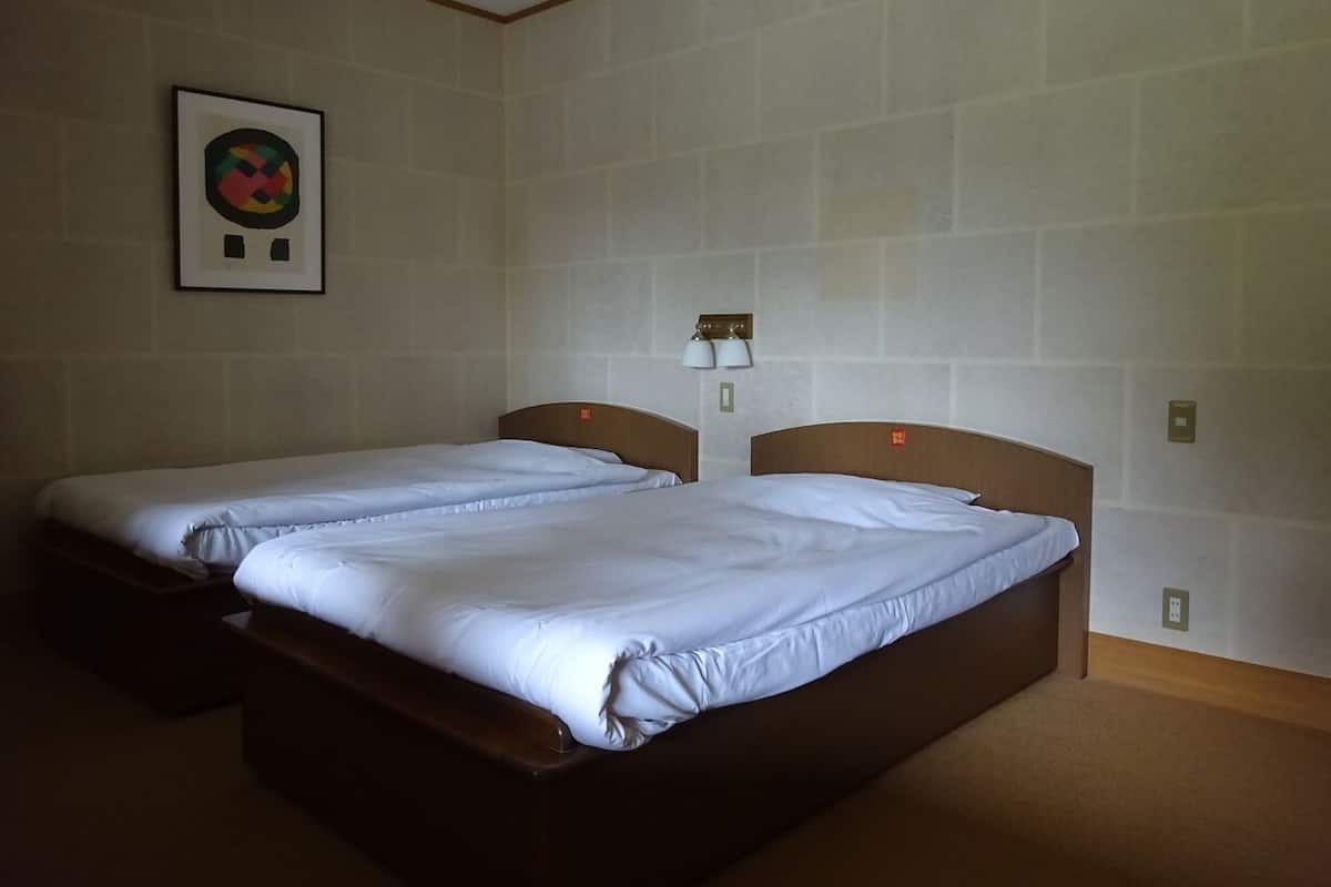 Quarto de hotel com duas camas, um quadro na parede e um abajur.