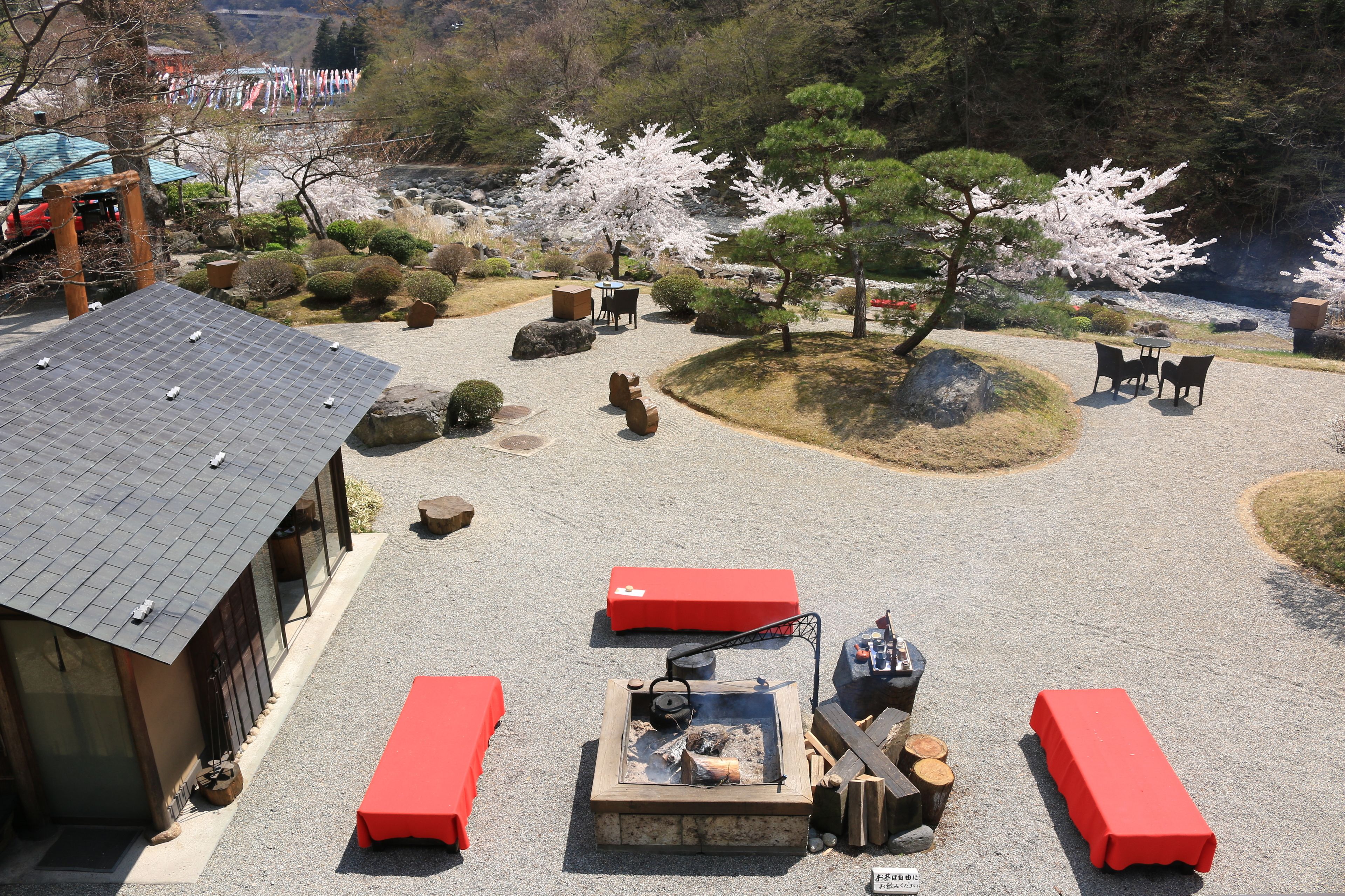A traditional Japanese garden with a stone lantern, a fire pit, and a wooden bench.