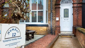 A traditional Yorkshire holiday house with a white door marked 'Num 12', a brick facade, and a small outdoor seating area. - ❤️ Large Family Self Catering Holiday House-Filey (Filey)