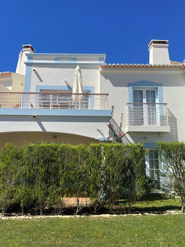 A two-story building with a balcony, a window, and a door.