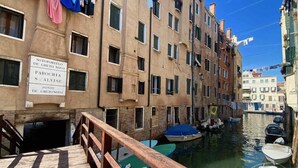 Un canal flanqueado por edificios, un puente de madera y barcos amarrados a lo largo del agua.