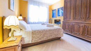Una habitación de hotel con cama, mesita de noche, televisor y armario.