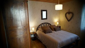 A cozy bedroom with a wooden headboard, a large mirror, a heart-shaped decoration, and two bedside lamps. - Cottage 4 people for lovers of the countryside (Poiseul-la-Ville-et-Laperrière)