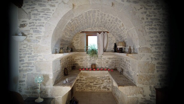 A stone-walled room with a bench, a potted plant, and various decorative items. - Cottage 4 people for lovers of the countryside (Poiseul-la-Ville-et-Laperrière)