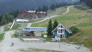 Ein Skigebiet mit Seilbahn, Parkplatz und einem mehrstöckigen Gebäude mit Balkonen.