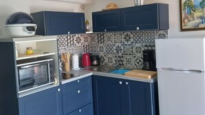 Eine Küche mit blauen Schränken, einem eingebauten Ofen, einer Kaffeemaschine und einem Kühlschrank.