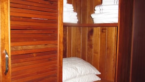 Un placard en bois avec des étagères où sont pliés des serviettes, et un oreiller blanc matelassé.
