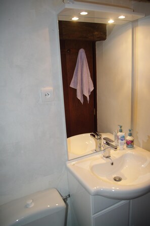 A bathroom with a white sink, a mirror, and a towel hanging on the door. - New gite in quiet spot within easy reach of amenities. + local attractions (Ju Belloc, Plaisance du Gers)